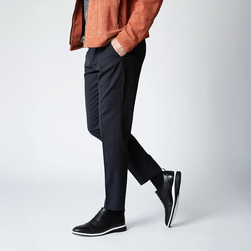 The Cap-Toe in Onyx Black and White worn by model with dark dress pants in studio
