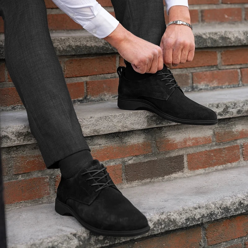 The Original Dress Shoe by Amberjack in Midnight Black - On Model Wearing Grey Suit Sitting Down on Stairs