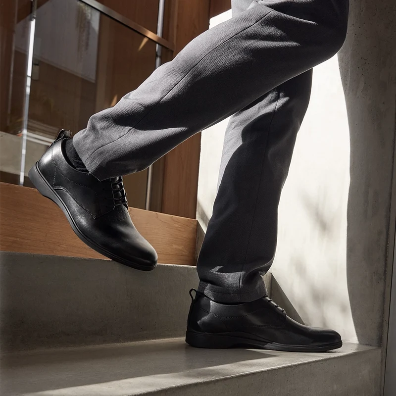 model wearing The Original Obsidian black leather paired with gray dress pants walking down stairs