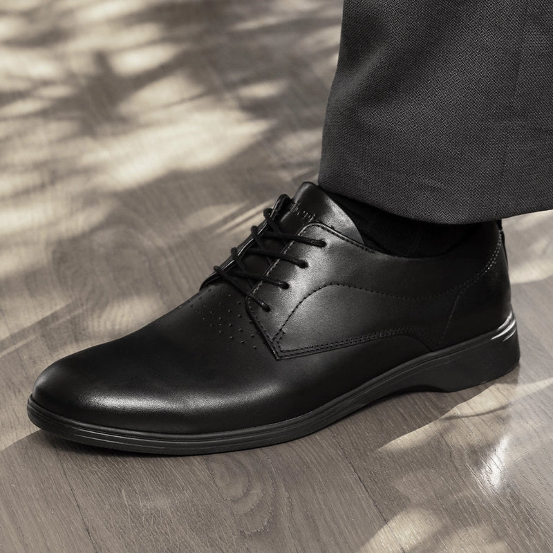The Original Dress Shoe by Amberjack in Obsidian Black - On model standing on chair wearing black dress pants